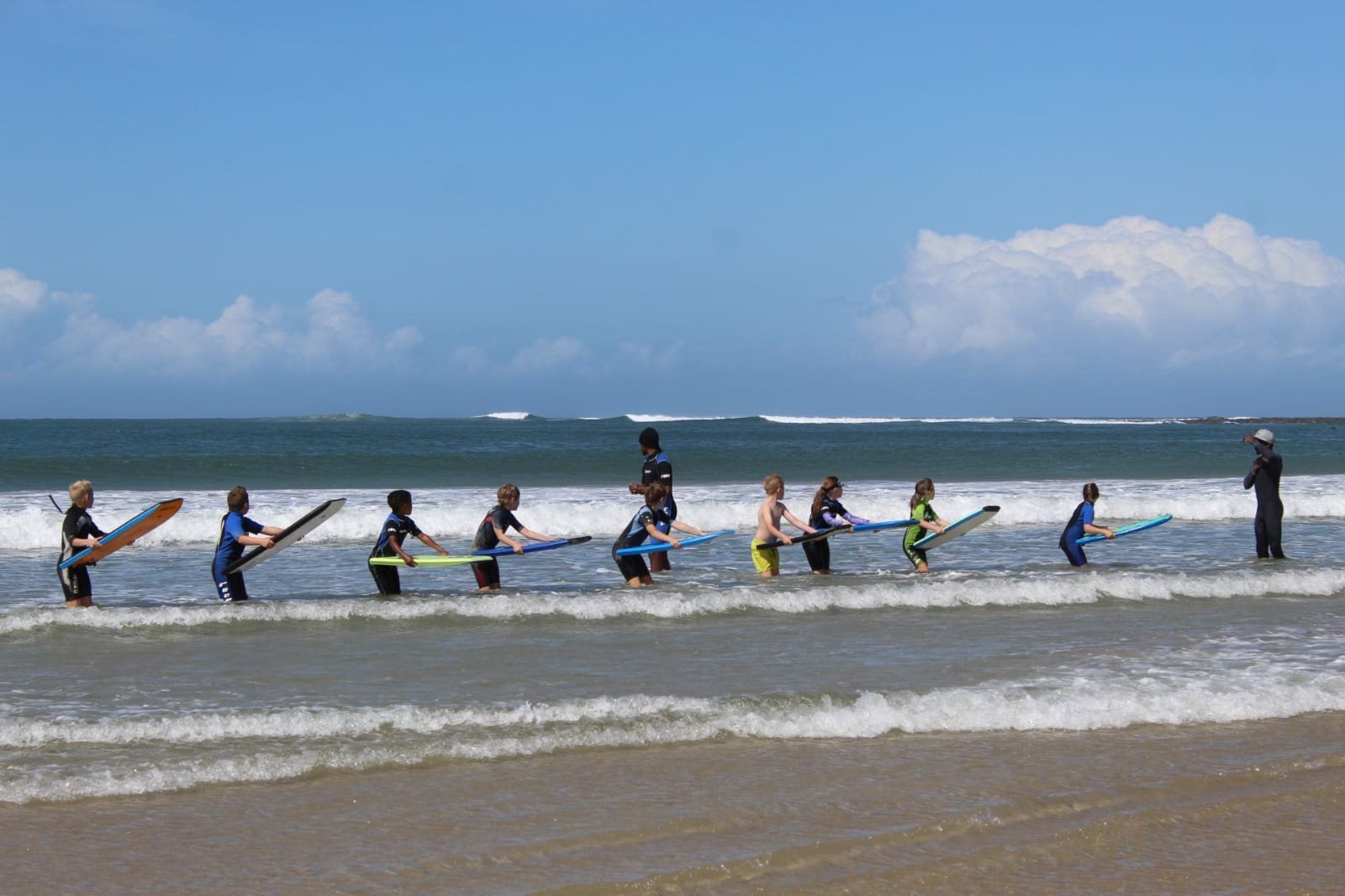 Learners lined up with boogie boards in the surf