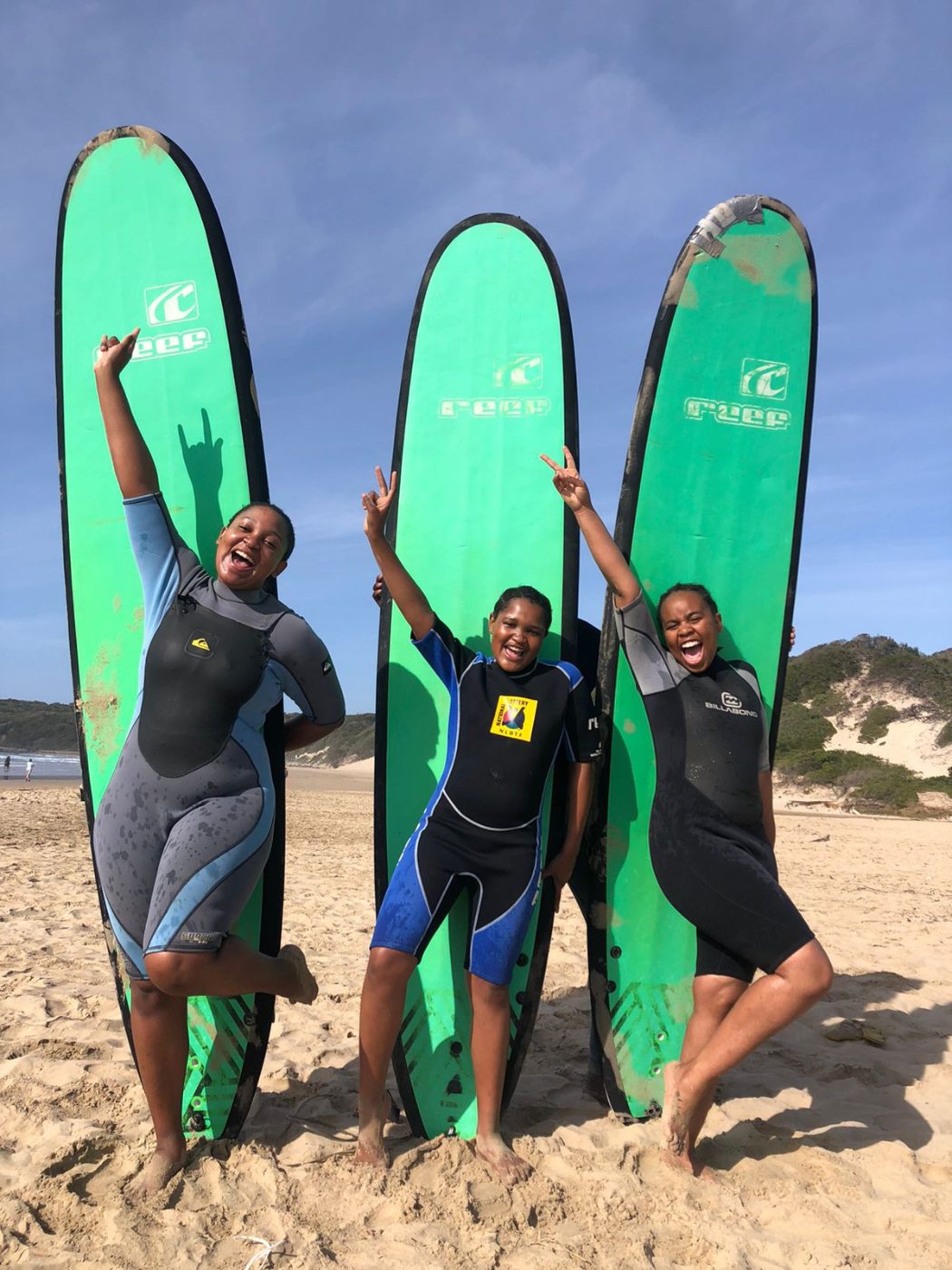 Three students celebrating with their surfboards