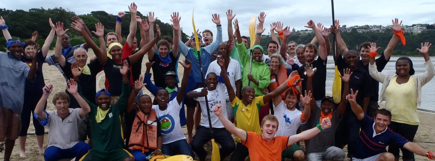 A corporate team cheering with paddles on the beach